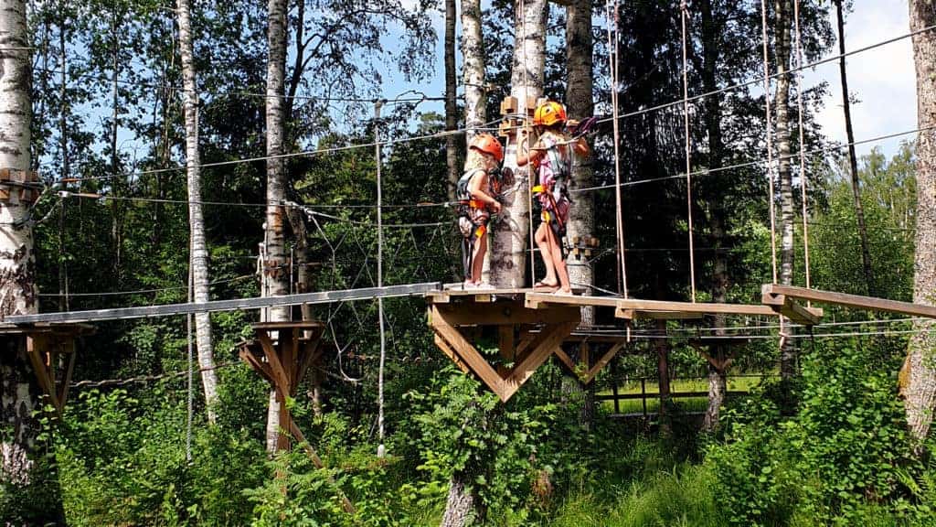 Två barn har sele och hjälm på sig när de går höghöjdsbanan för barn.