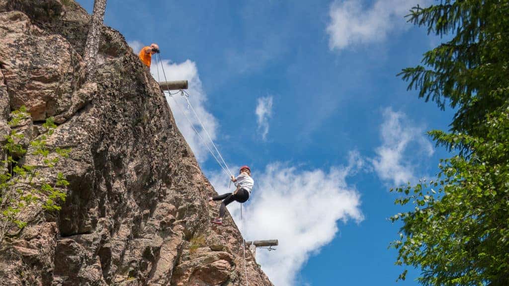 A man makes his way down a mountain using ropes.